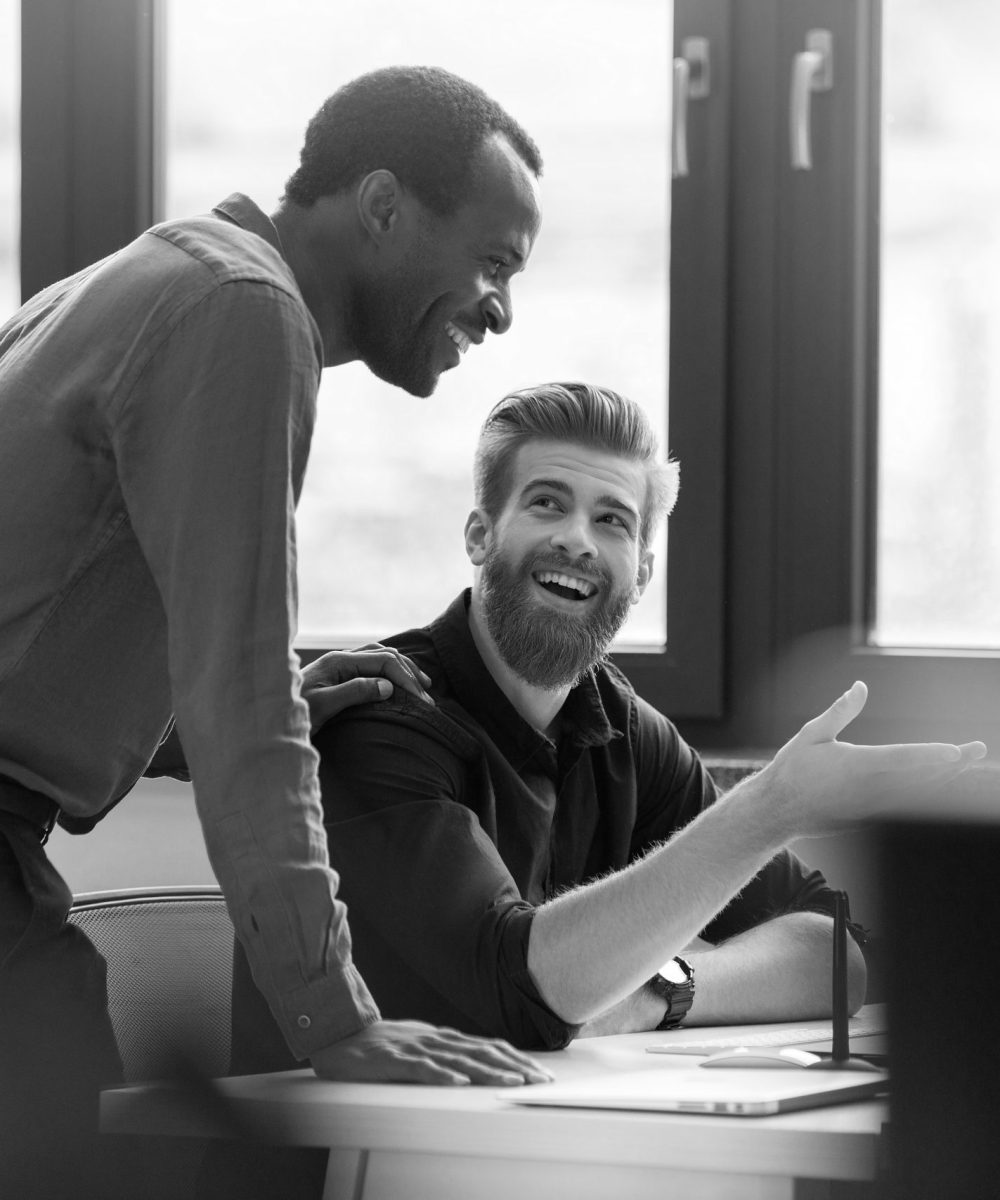 Two happy smiling men working together on a new business project at a workplace